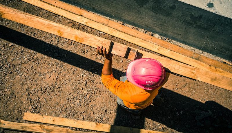 construction-site-with-worker-carrying-lumber_t20_7JOngv